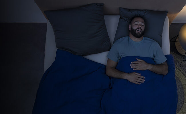 Homem deitado numa cama dorme de boca aberta